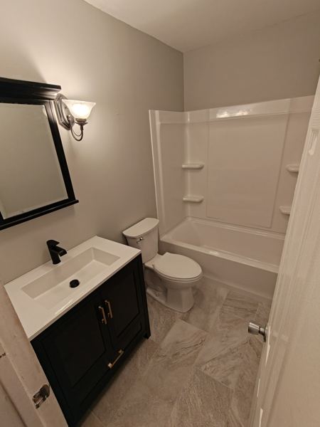Bathroom remodel after: new black vanity, mirror and plank floor