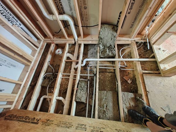 Floor opened up for new PVC drain and vent rough-in under a bathroom