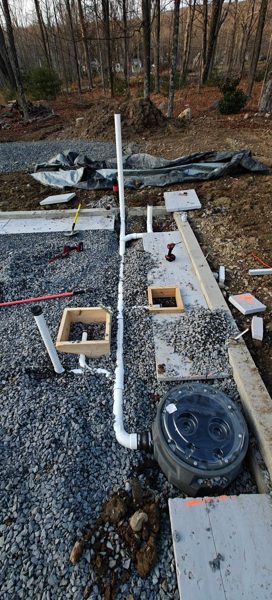 New PVC drain lines and cleanouts set in gravel before the slab pour