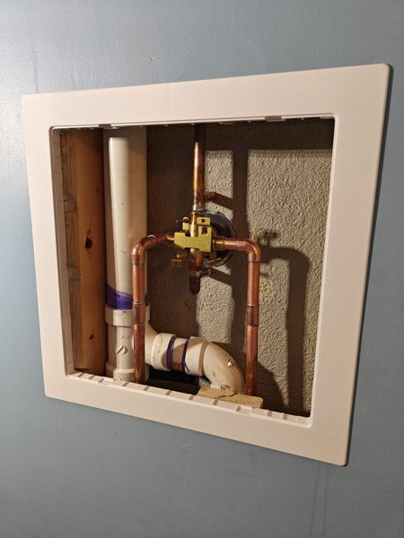 New shower valve and copper piping behind an access opening